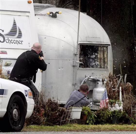 A Clark County deputy, left, and German Township Patrolman Jeremy Blum, right, open fire on a trailer Saturday at Enon Beach near Enon, Ohio. 